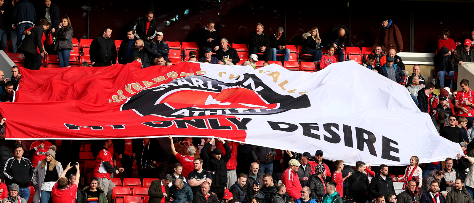 Supporters hold a flag aloft at The Valley