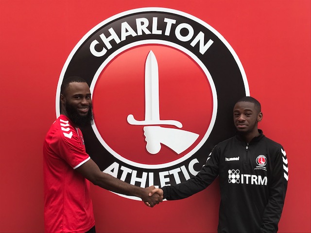 Image of Gabriel Affiku shaking hands with a CACT employee in front of the Charlton Athletic logo