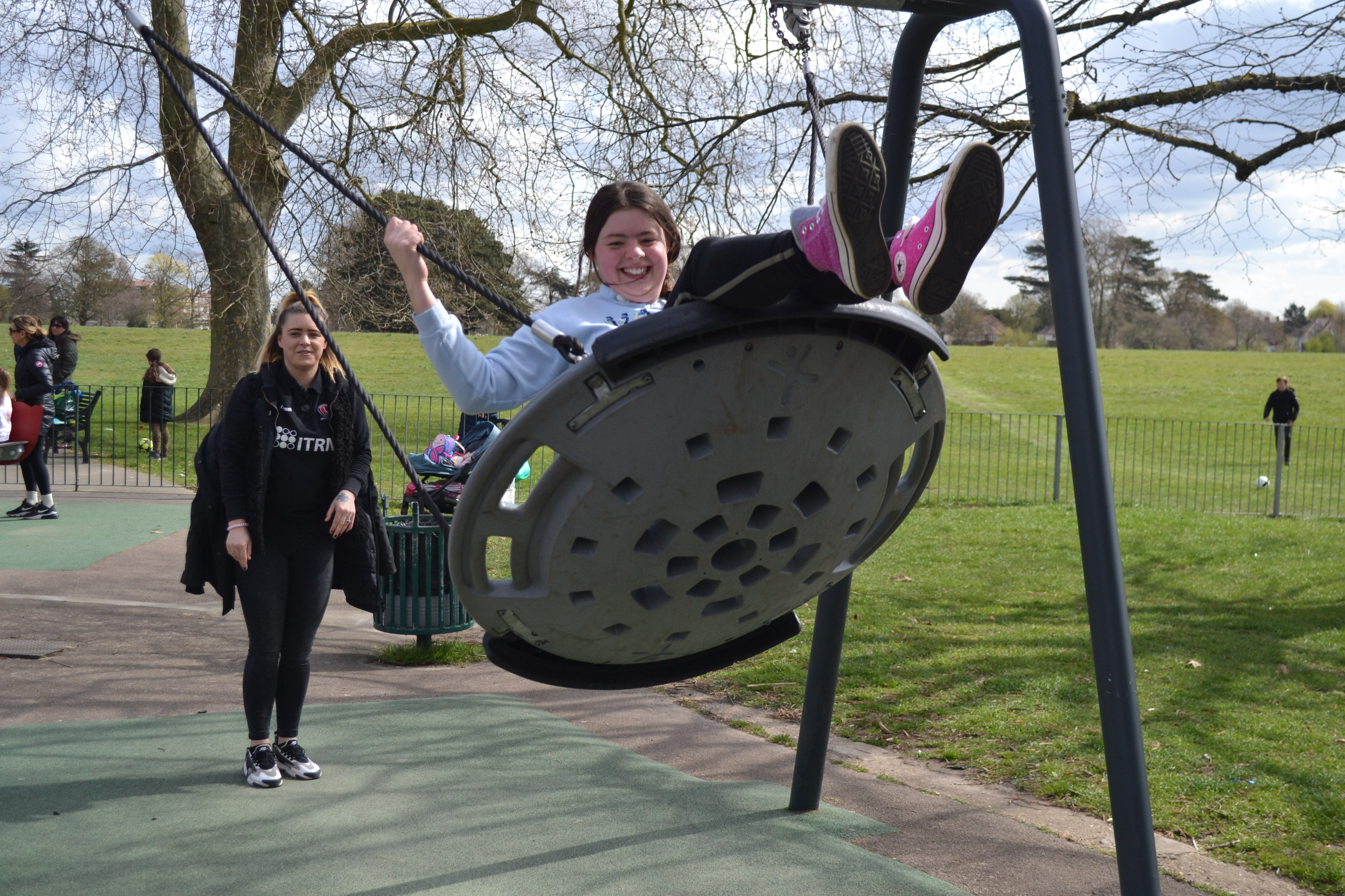 Image of a Short Breaks participant being pushed on a swing by a CACT staff member