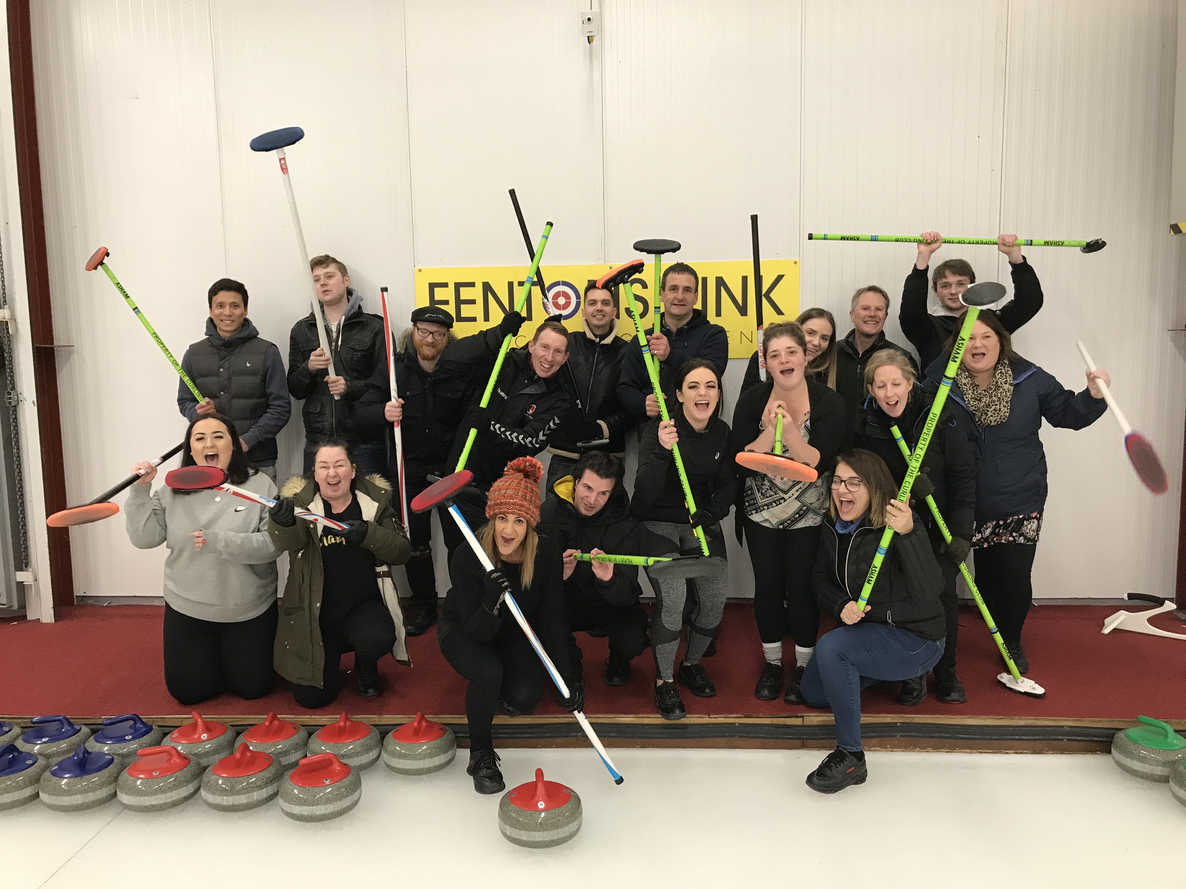 A group of mental health clients holding up curling brooms