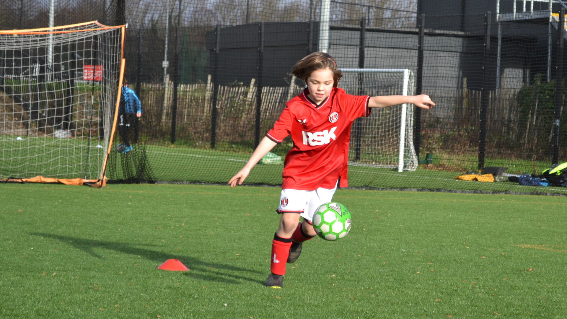 Young girl kicking a ball in Charlton kit
