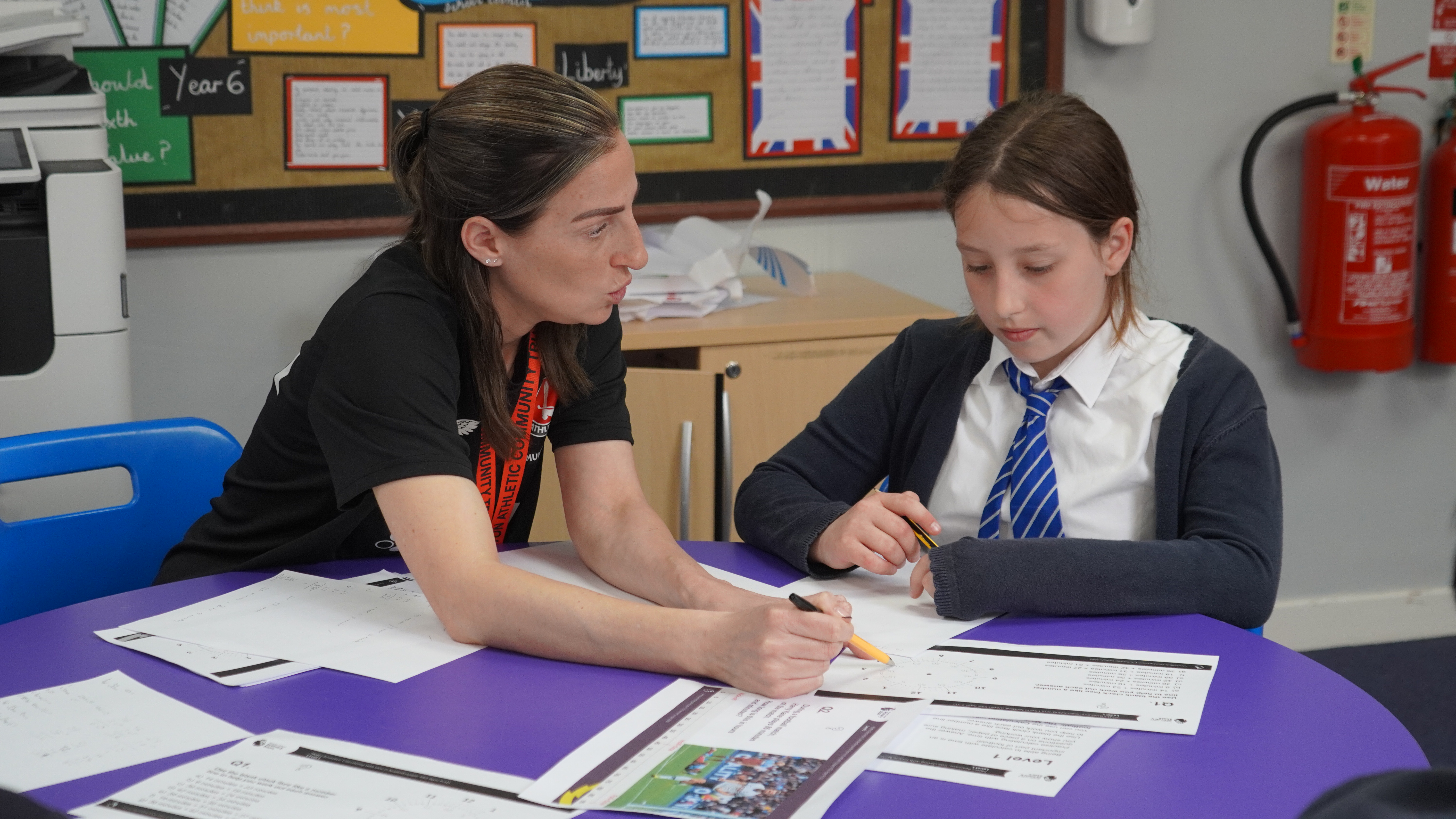 Premier League Primary Stars staff member explaining a question with a student