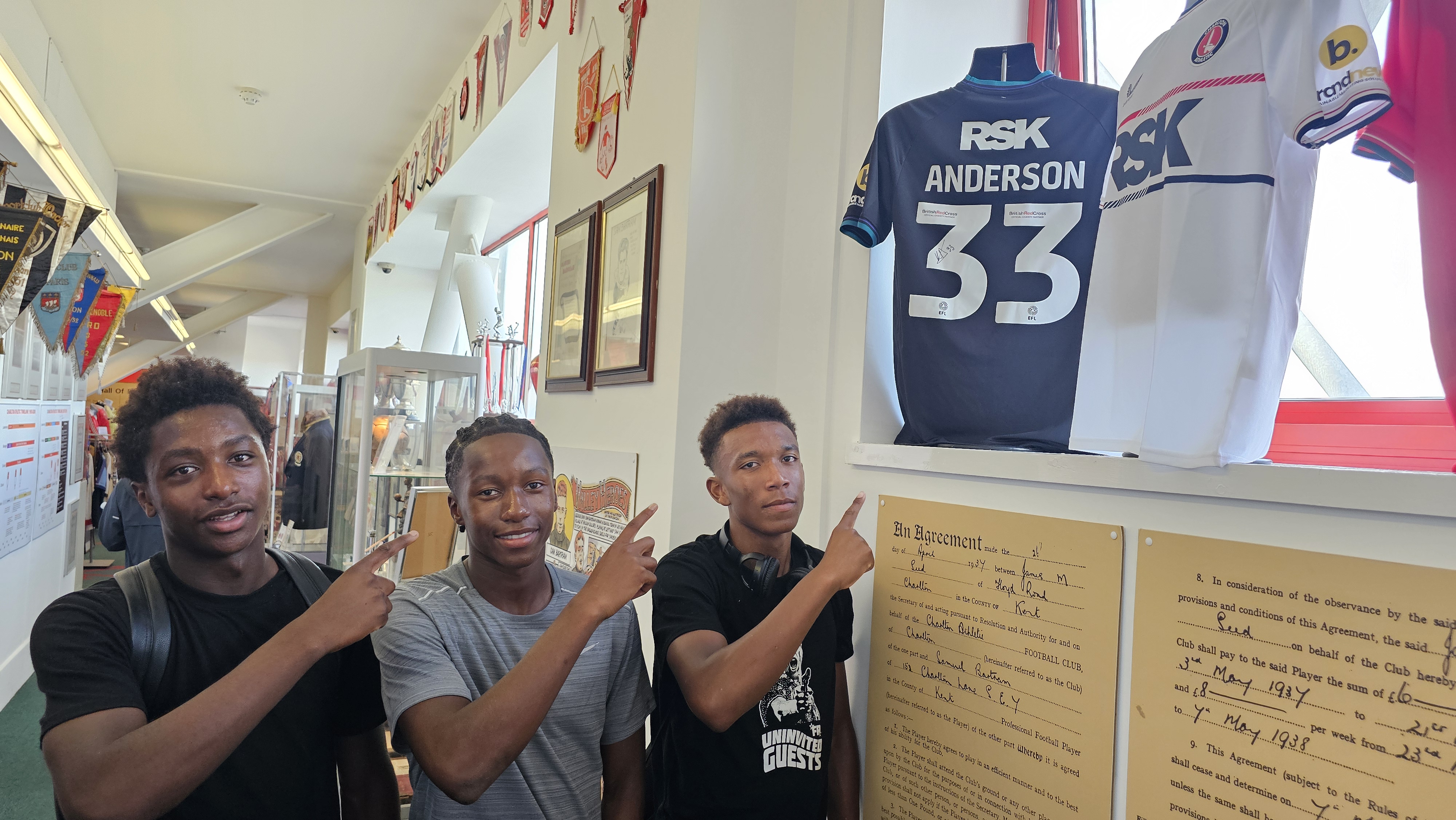 Alan Mwamba, Ibrahim Fullah and Ethan Brown point to a shirt worn by Karoy Anderson