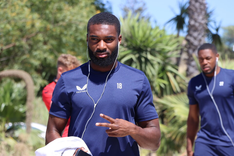 Mandela Egbo with a peace sign as he walks back to the team's hotel with his earphones in