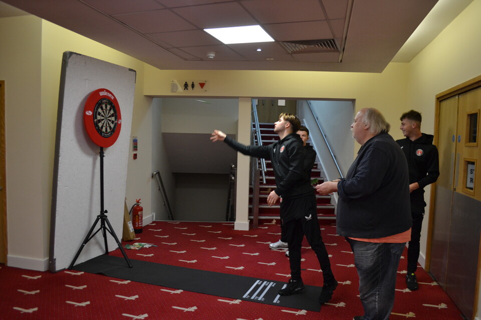 U21 players playing darts against an Extra Time attendee