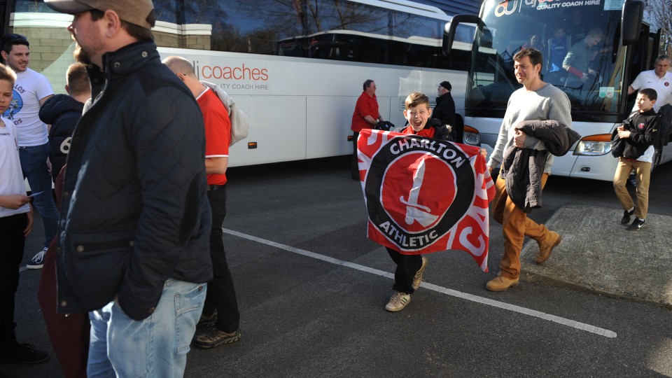 A young Charlton fan shows his colours as he leaves the bus
