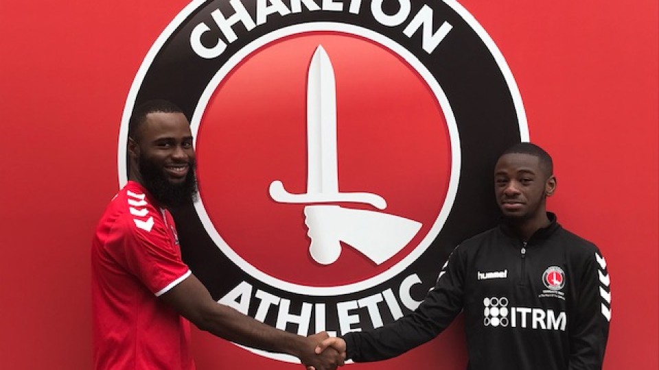 Image of Gabriel Affiku shaking hands with a CACT employee in front of the Charlton Athletic logo