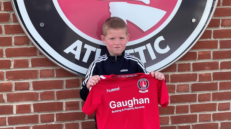 Portrait of Josh Hunt holding up a Charlton shirt
