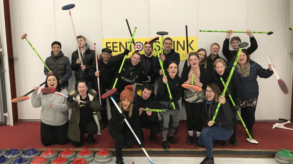 A group of mental health clients holding up curling brooms