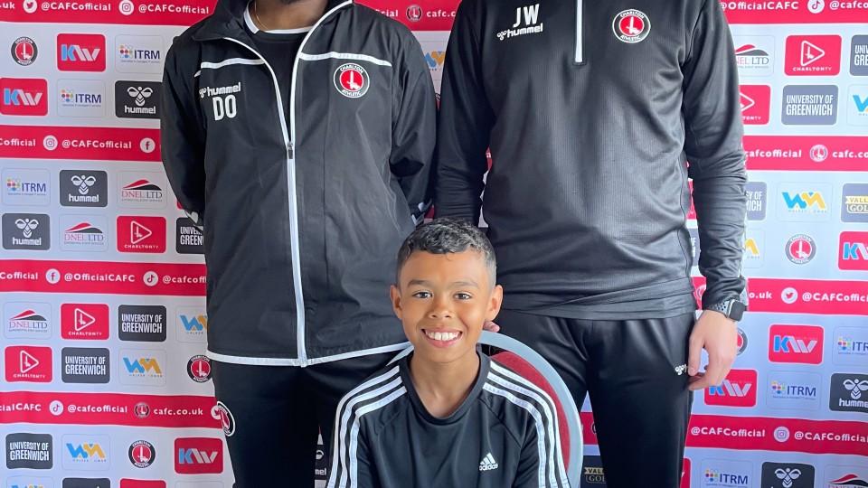 Jake Maloney signing his contract at a small table alongside CAFC Academy staff